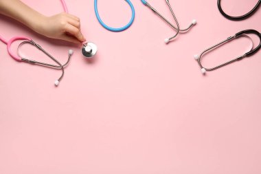 Pembe arka planda steteskoplu kadın eli. Dünya Sağlık Günü