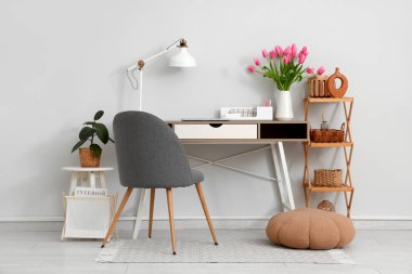 Raflar, dizüstü bilgisayarlar ve vazoda güzel lale çiçekleri olan modern işyeri.