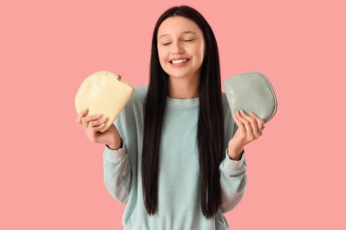 Pembe arka planda kozmetik torbaları olan genç bir kız.