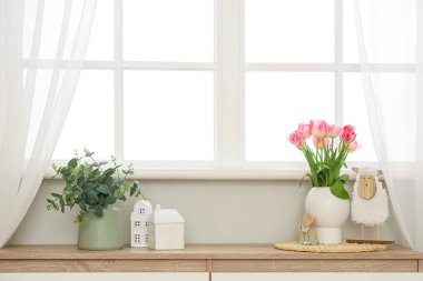 Laleli vazo ve odanın penceresinin yanındaki rafta Paskalya dekoru.