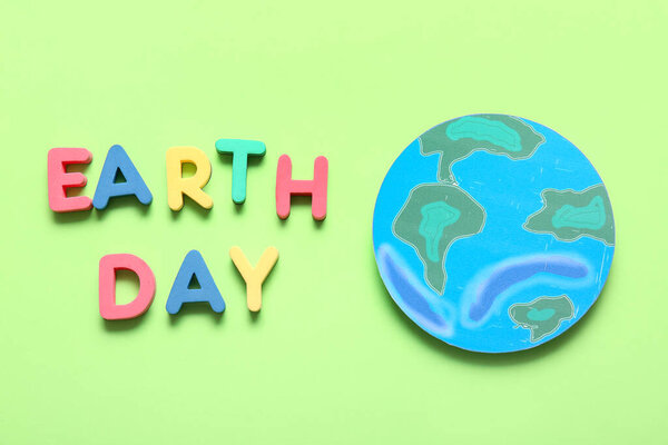 Бумажная планета Земля и слова ДЕНЬ ЗЕМЛЯ на зеленом фоне