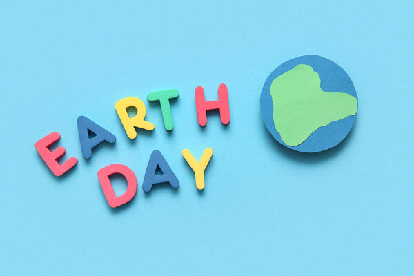 Бумажная планета Земля и слова ДЕНЬ ЗЕМЛЯ на синем фоне