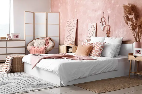 Şık bir yatak odası, rahat bir yatak odası ve komodinin üzerinde otlar.