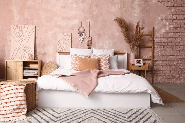 Şık bir yatak odası, rahat bir yatak odası ve komodinin üzerinde otlar.