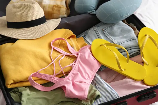 Otel odasında içinde giysiler ve parmak arası terlikler olan bavulları boşalttım.