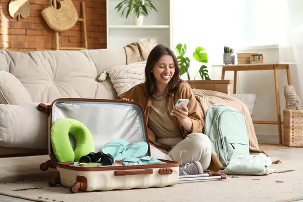 Güzel genç bir kadın bavulunu evde kıyafetleriyle açıyor.