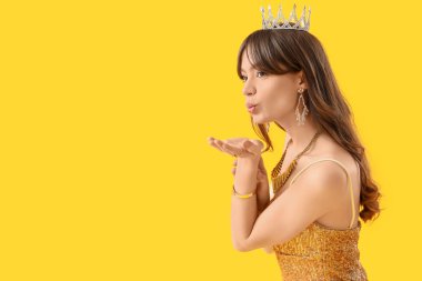 Balo elbisesi giymiş, sarı arka planda öpüşen güzel bir kadın.