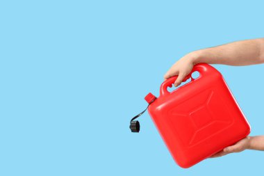 Erkek eller mavi arka planda teneke kutu tutuyor.