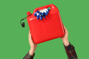 Erkek eli, yeşil arka planda eldivenli teneke kutu tutuyor.