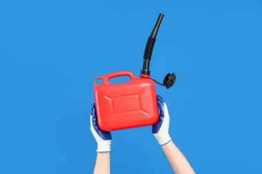 Mavi arka planda lastik başlıklı teneke kutu tutan erkek eller.