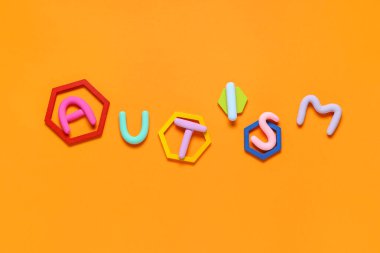 Kelime AUTISM turuncu arka planda plastikinden yapılır