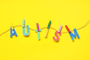 Kelime AUTISM sarı arka planda asılı halat