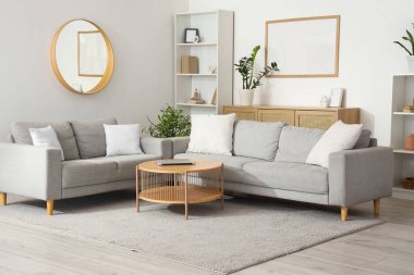 Gri kanepeli, aynalı ve boş çerçeveli aydınlık oturma odasının içi