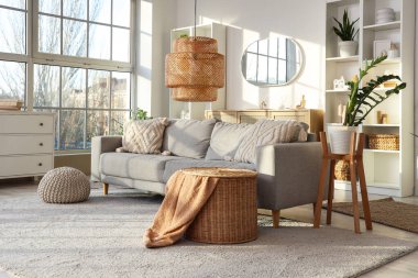 Gri kanepeli, raf üniteli ve aynalı aydınlık oturma odasının içi.