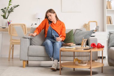 Evde kanepede çalışan, dizüstü bilgisayarı olan stresli genç kız.