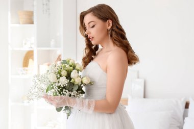 Yatak odasında düğün buketi olan güzel gelin.