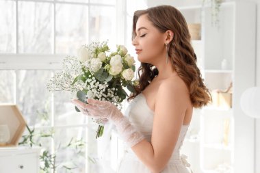 Yatak odasında düğün buketi olan güzel gelin.