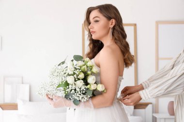 Yatak odasında düğün buketi olan güzel gelin.