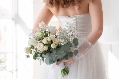 Yatak odasında düğün buketi olan güzel gelin, arka manzara.