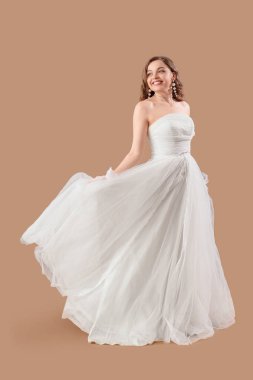 Bej arka planda beyaz gelinlik içinde güzel gelin.