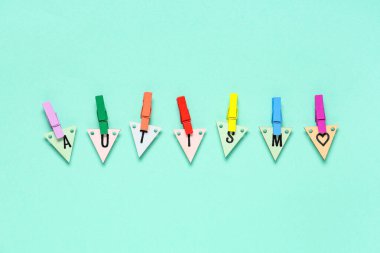 Kelime AUTISM renk arka planında renkli mandallarla ahşap üçgenlerden oluşur