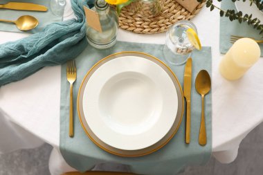 Lokantada altın çatal bıçak ve mumlarla süslenmiş şık bir masa.