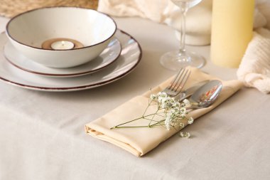 Yanan mum, temiz tabaklar ve restoranda güzel çiçekler olan zarif bir masa.