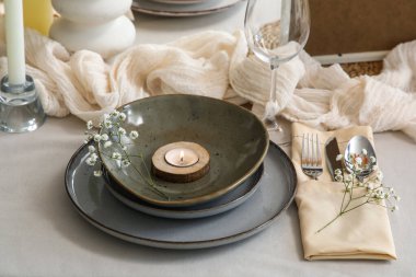 Yanan mumla dolu temiz tabak ve restoranda servis edilen masada güzel çiçekler, yakın plan.