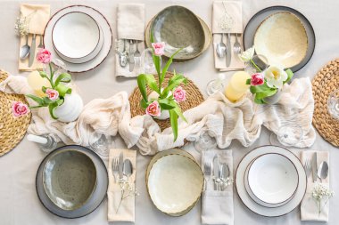 Lokantada güzel lale çiçekleri, mumlar ve temiz tabaklar olan şık bir masa.