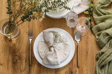 Restoranda sunulan ahşap masa üzerinde katlanmış peçete ve güzel çiçeklerle dolu bir tabak.