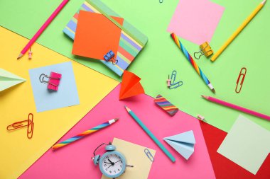 Renkli arka planda kağıt uçaklar olan okul kırtasiyesi.