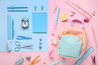 Renk arkaplan üzerinde sırt çantası ve alarm saati olan okul kırtasiyesi