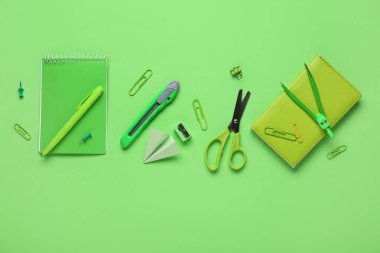 Yeşil arka planda kağıt uçakla okul kırtasiyesi