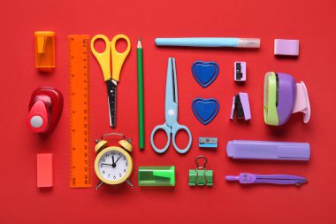 Kırmızı arkaplanda alarm saati olan okul kırtasiyesi