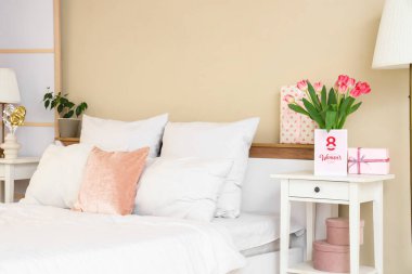 Yatak odasındaki kadınlar günü için laleli vazo, hediye ve tebrik kartı.