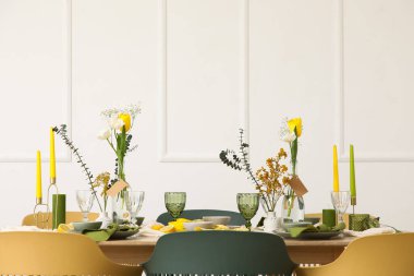 Odada ışık duvarının yanında bahar çiçekleri olan masa ayarı