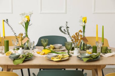 Odada ışık duvarının yanında bahar çiçekleri olan masa ayarı