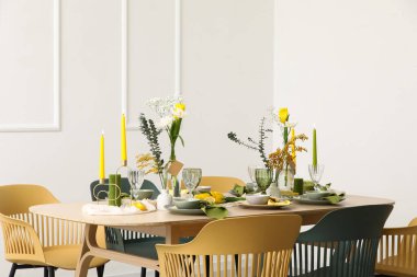 Odada ışık duvarının yanında bahar çiçekleri olan masa ayarı