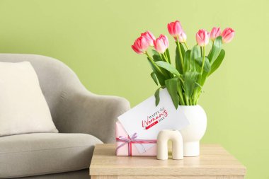 Kadınlar Günü için laleli vazo, hediye ve tebrik kartı oturma odasındaki masada.