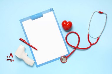 Steteskoplu boş bir pano, kızılötesi termometre ve mavi arka planda haplar. Dünya Sağlık Günü