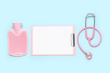 Steteskoplu boş bir pano ve mavi arka planda sıcak su şişesi. Dünya Sağlık Günü