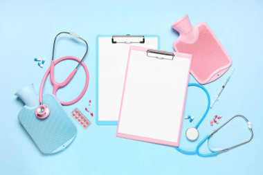 Stetoskoplu boş panolar, haplar ve mavi arka planda sıcak su şişeleri. Dünya Sağlık Günü