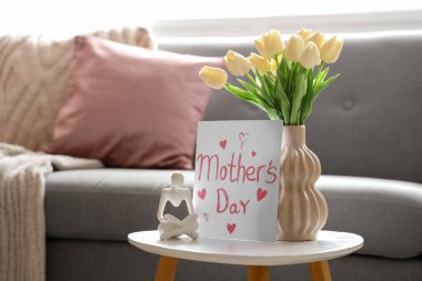 Anneler günü için lale, heykel ve kartla dolu vazo oturma odasındaki masada.