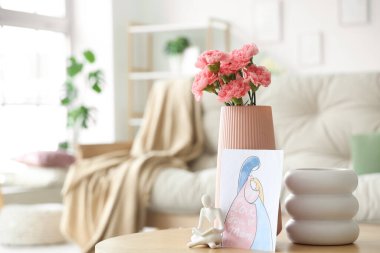 İçinde karanfil çiçekleri olan vazo ve Anneler Günü kartı oturma odasındaki masada, yakın plan.