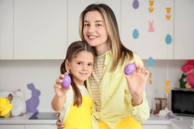 Mutlu anne ve küçük tatlı kızı neşeli mutfakta boyanmış Paskalya yumurtalarıyla