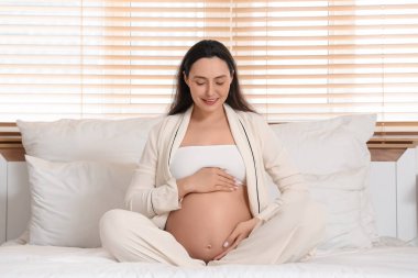 Genç hamile kadın yatak odasında oturuyordu