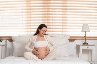 Genç hamile kadın yatak odasında oturuyordu