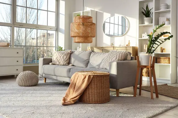 Gri kanepeli, raf üniteli ve aynalı aydınlık oturma odasının içi.
