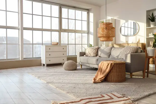 Gri kanepeli, raf üniteli ve aynalı aydınlık oturma odasının içi.