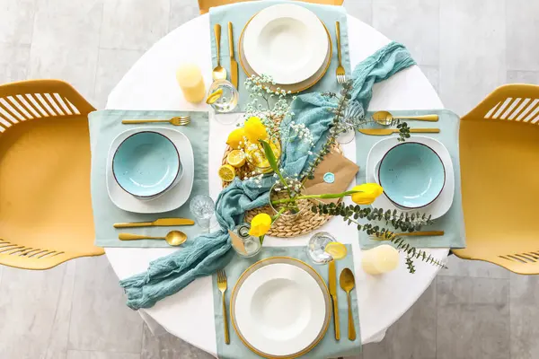 Lokantada güzel lale çiçekleri, mumlar ve altın çatal bıçak seti olan şık bir masa.